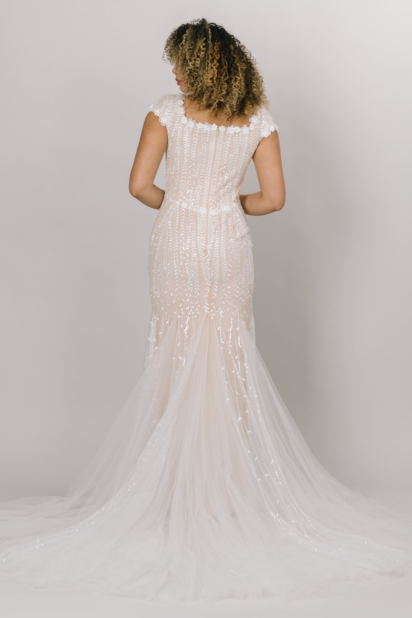 Back view of modest wedding dress, fitted silhouette with a square neckline. Champagne color underlining color with a delicate lace overtop.  