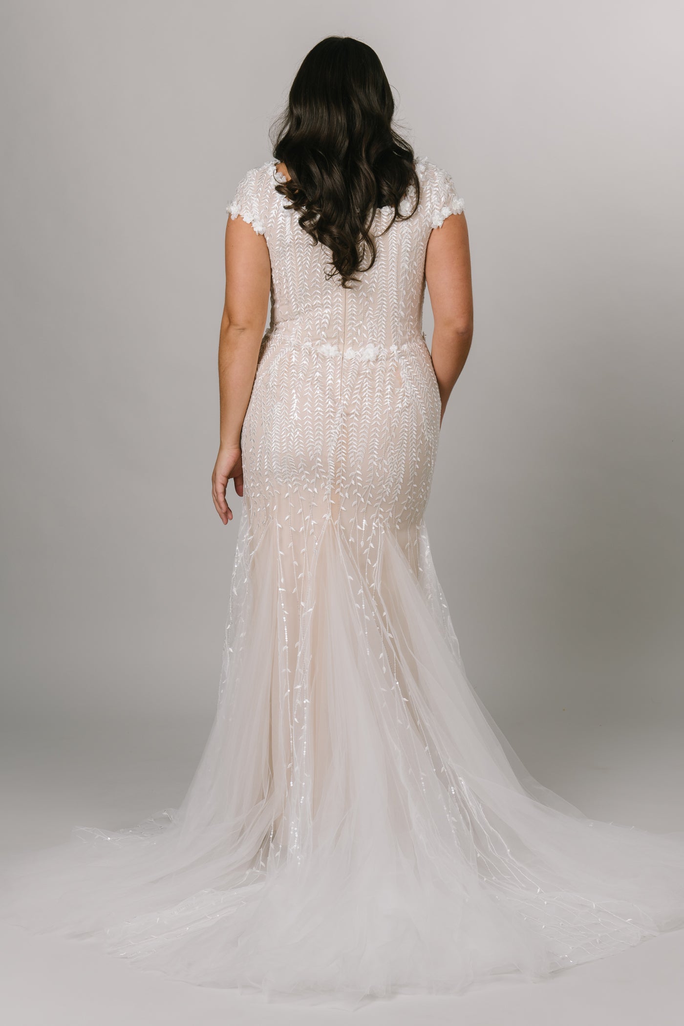 Plus size modest wedding dress, fitted silhouette with a square neckline. Champagne color underlining color with a delicate lace overtop.  