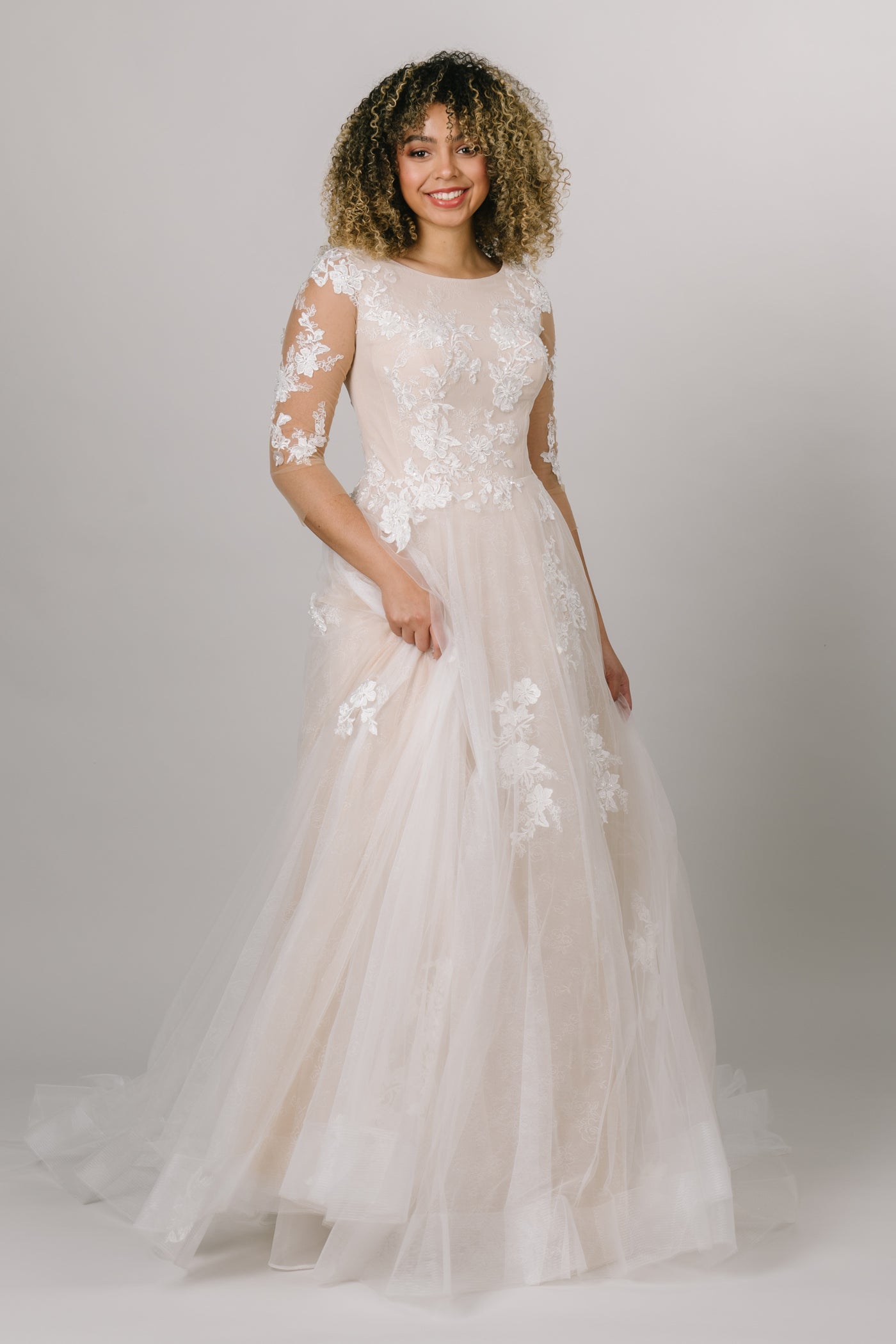 modest wedding dress is the whimsical gown of our dreams! With a soft lace print under the top layer of appliques, mesh sleeves, and a scoop neck, you'll be dancing the night away. 