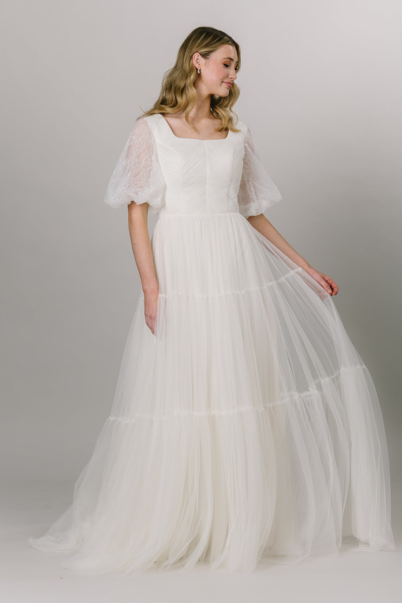 Alternate view of this beautiful english tulle wedding dress. This modest wedding wedding is perfect any whimsical bride. It has stunning lace puffed sleeves and a square neckline. It's a-line fit and tiered skirt.