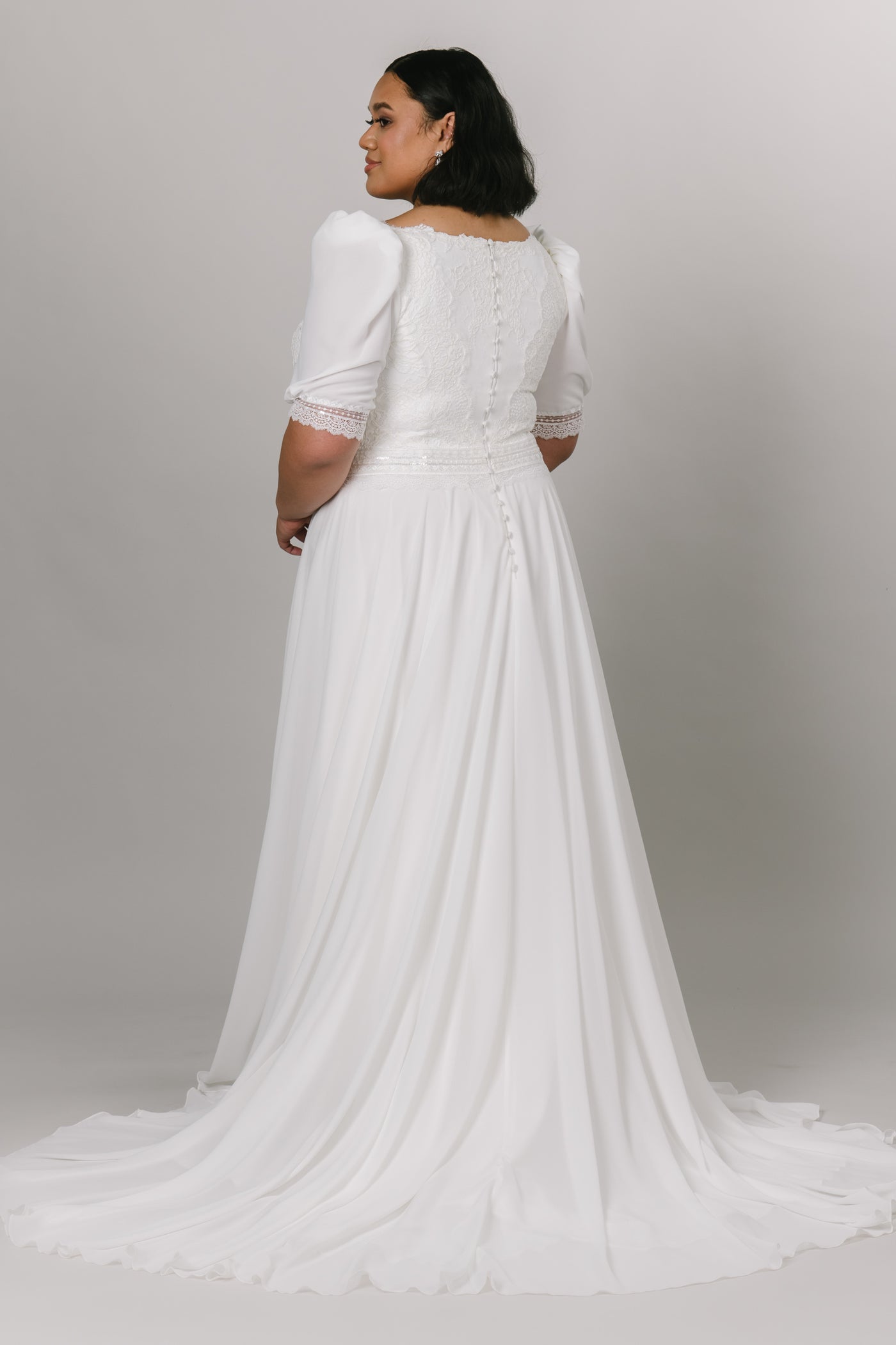 Plus size of modest wedding dress with a-line silhouette and v-neckline. The bottom is made with chiffon fabric and the top is has delicate lace with puffed sleeves.