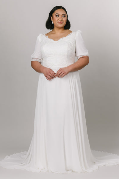 Plus size of modest wedding dress with a-line silhouette and v-neckline. The bottom is made with chiffon fabric and the top is has delicate lace with puffed sleeves. 