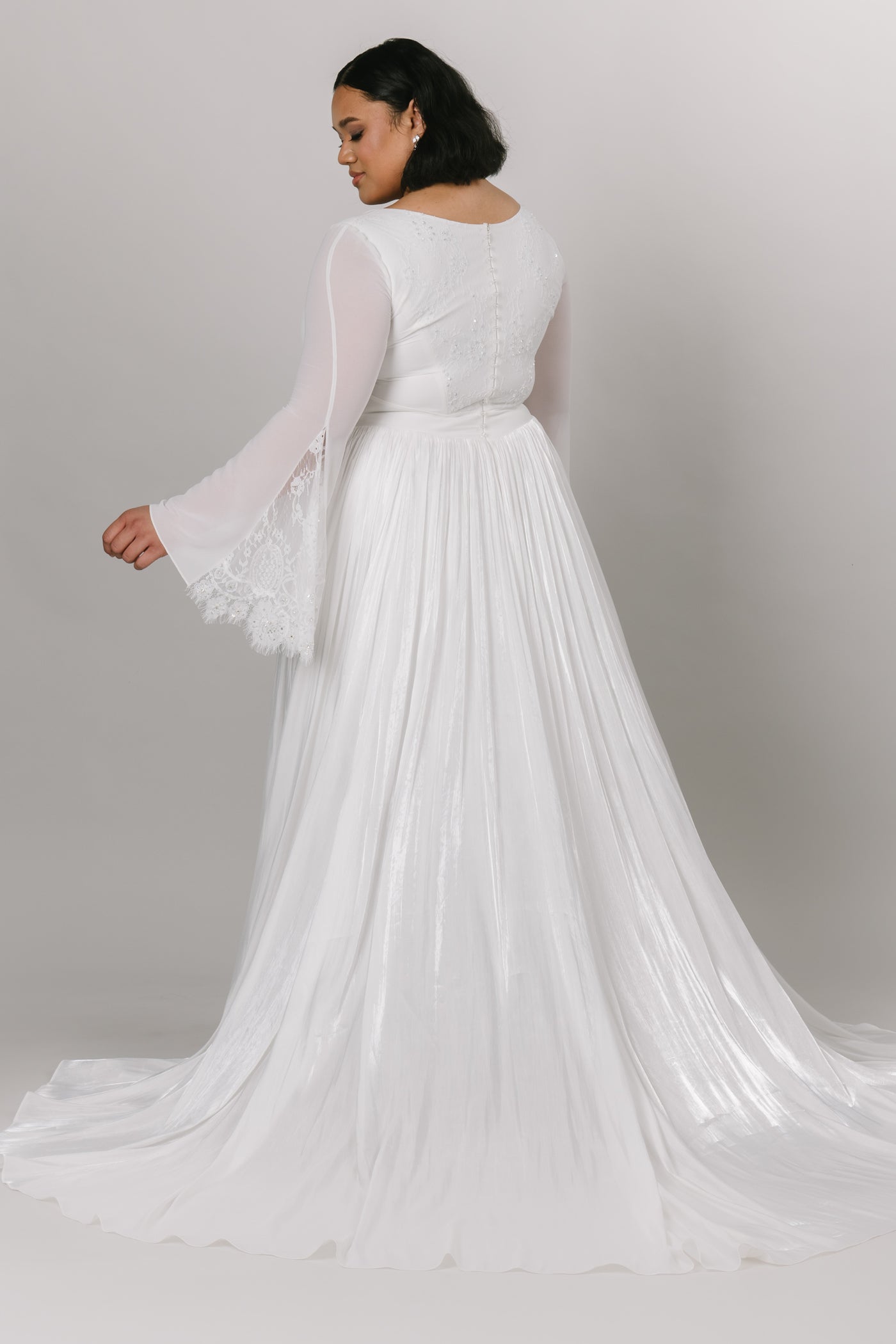 Back view of elegant modest wedding dress with chiffon bell sleeves. This Moments Made Bridal dress has a v-neckline and aline fit. It has chiffon layers and is so flowy. This dress is perfect for twirling and enjoying your wedding day.