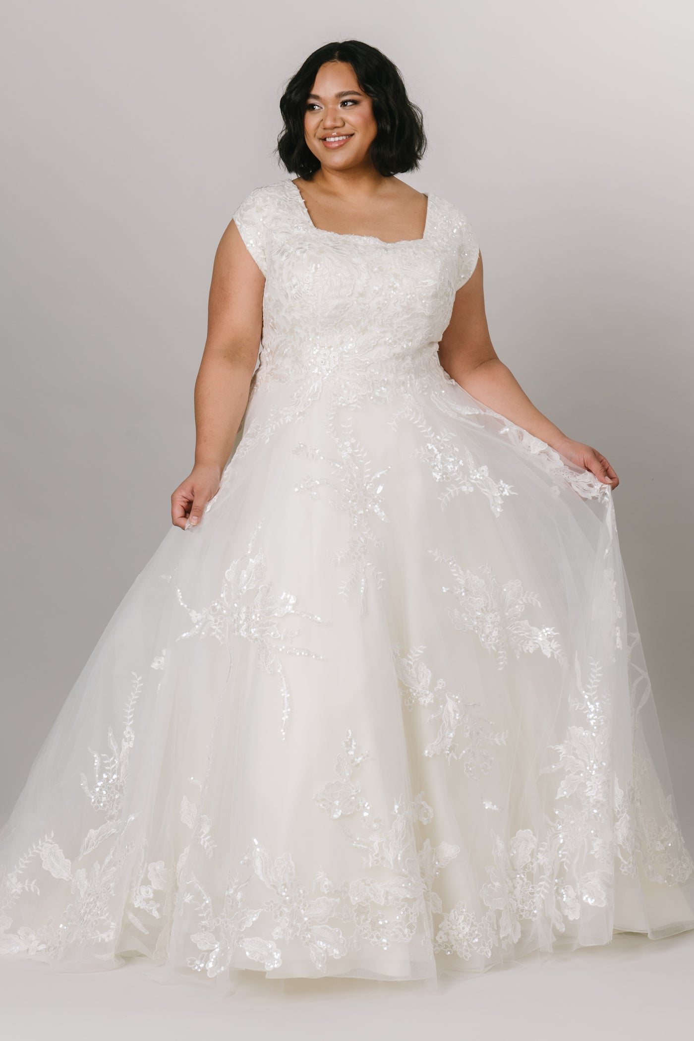 Plus size. Front view of modest wedding dress featuring a beautiful square neckline and ballgown silhouette.