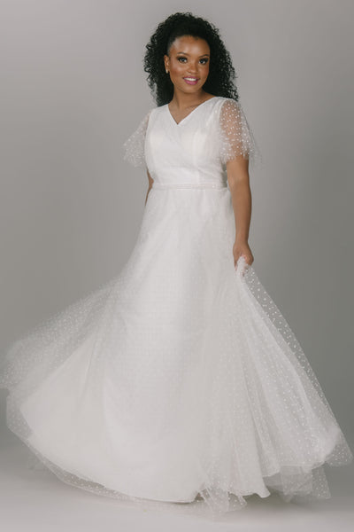 Party modest wedding dress with swiss dots. This dress has flutter sleeves and a sparkly thin belt. This v-neckline dress is the perfect modest wedding dress.