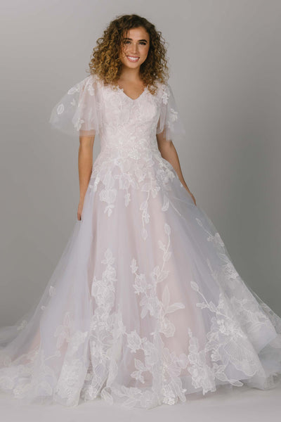 Front view of modest wedding ballgown. It has large tulle flutter sleeves. Beautiful flower lace covers the dress. It has a v-neckline and a train. 