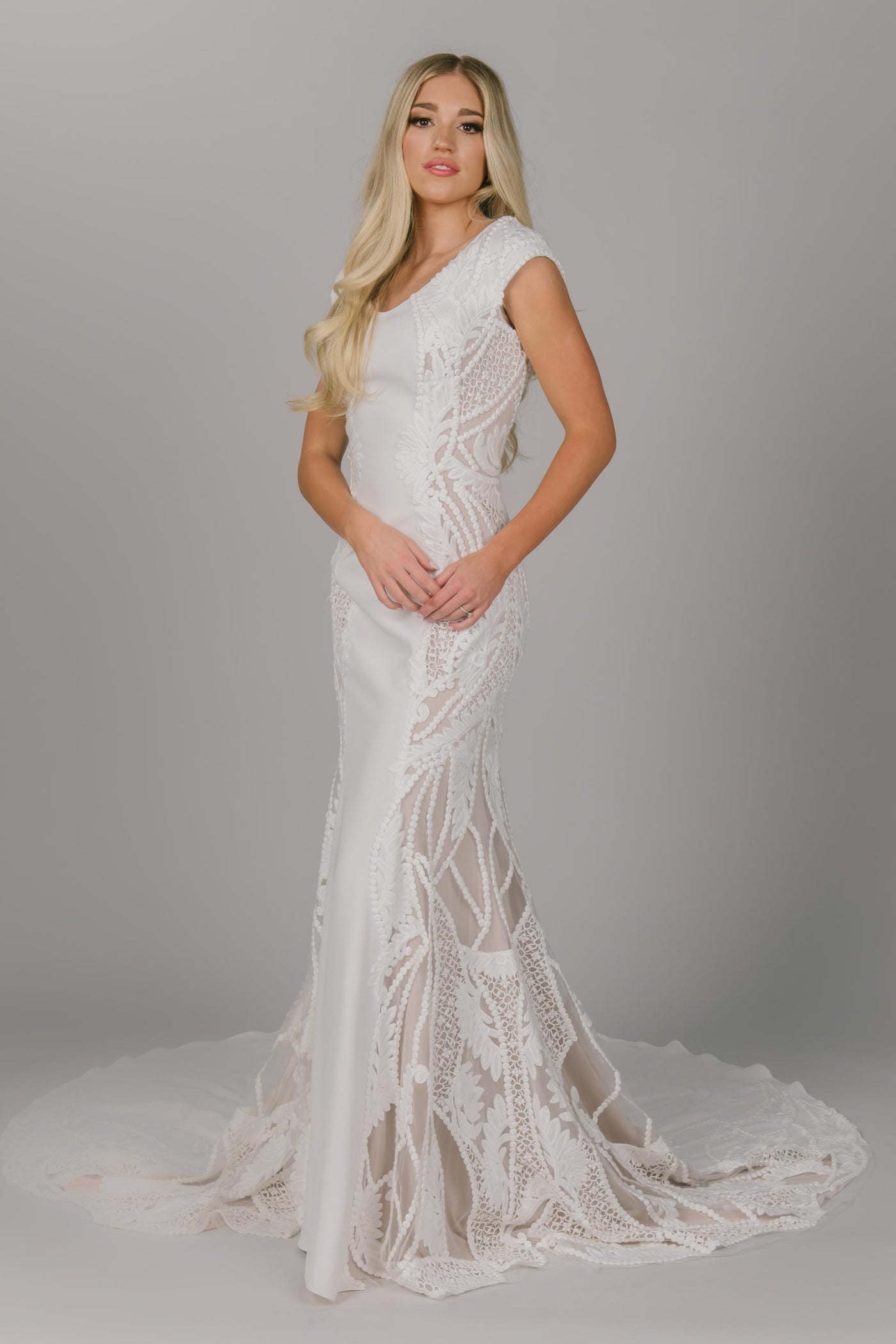 Boho style modest wedding dress. It has larger soft lace on the sides of the dresses. It has a v-neckline and has a fitted fit. It is cap sleeved but easy to move in.