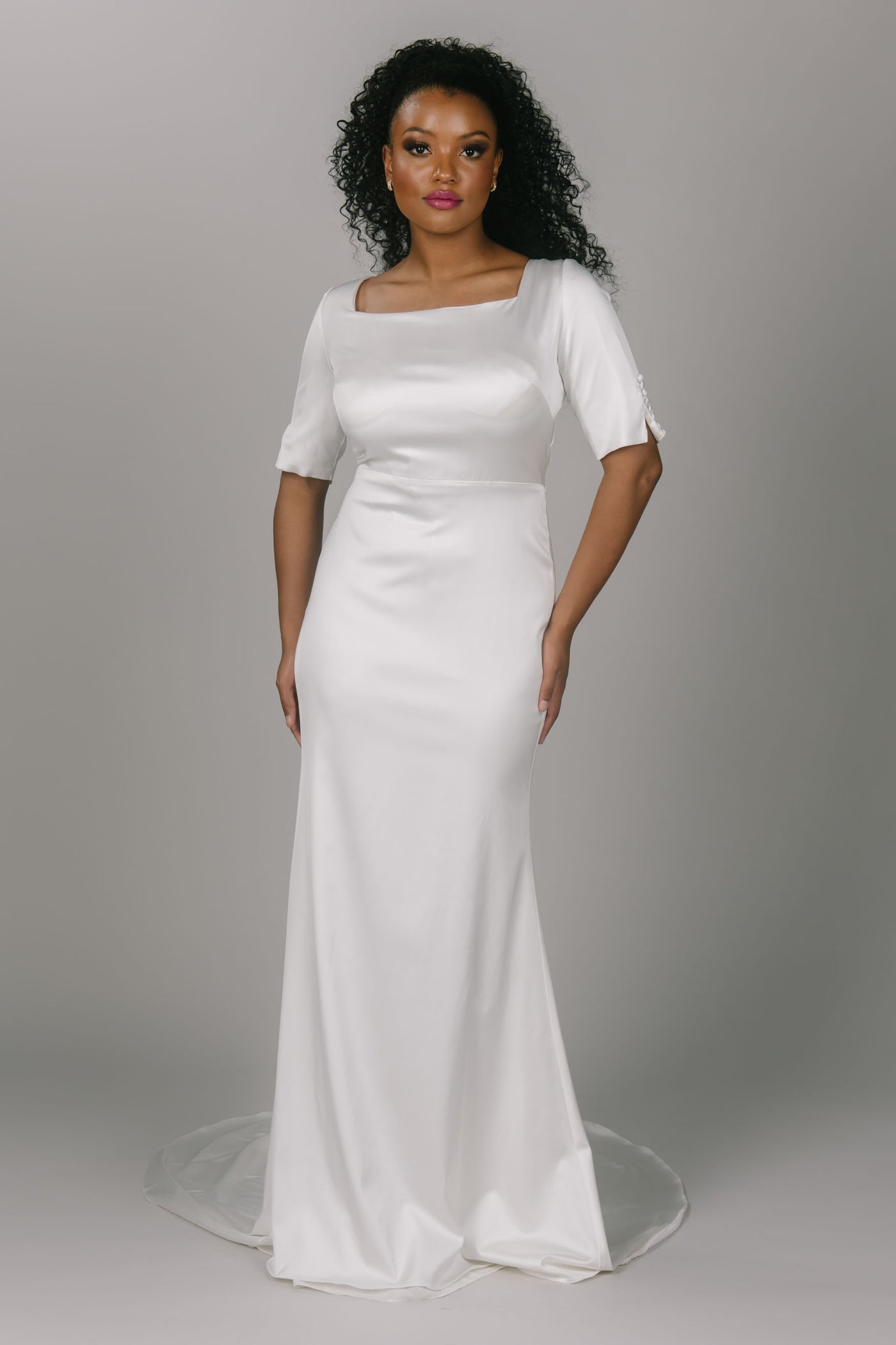 Modern and modest wedding dress. This dress is completely satin with covered buttons on the sleeves and all the way down the back of the dress. It has a square neckline and three quarter length sleeves. It is a looser fitted dress and absolutely perfect for the modest wedding dress bride.